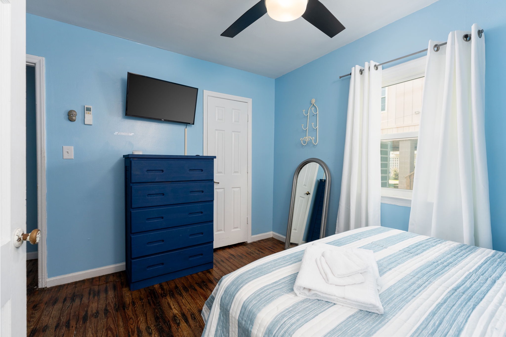 Relax in your serene blue bedroom with plush linens, a smart TV, ceiling fan, and plenty of storage. Wake refreshed and ready to explore.