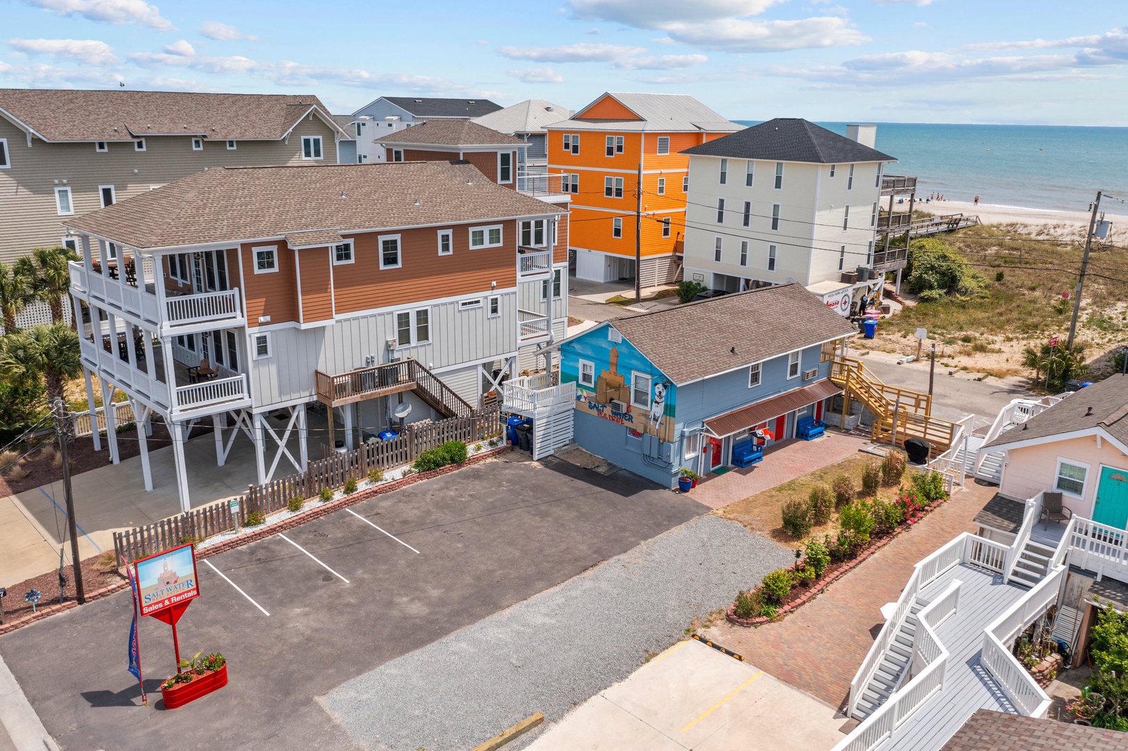 Colorful beachfront vacation homes create a vibrant coastal community just steps from the sandy shore and ocean waves.
