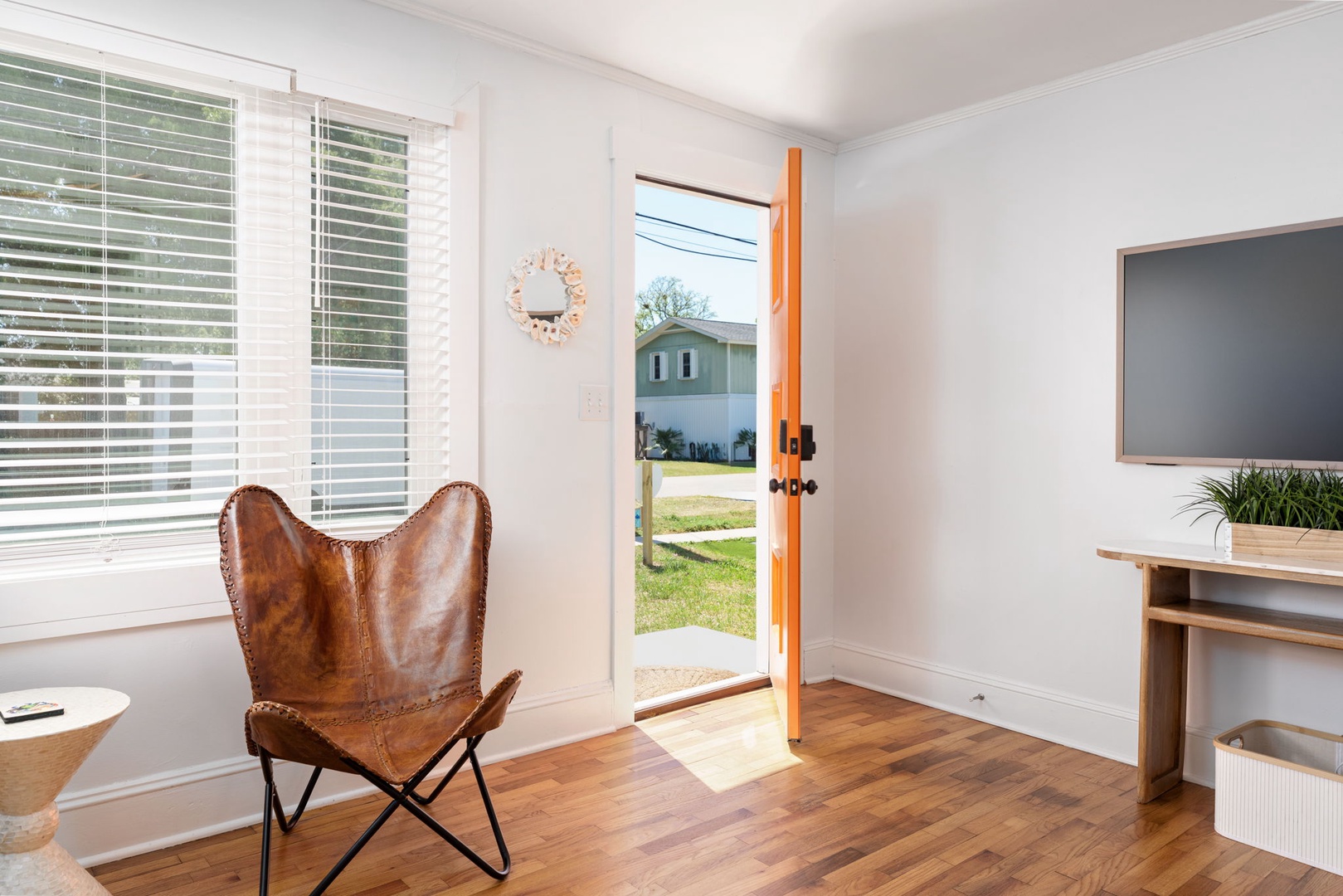 Relax in your stylish leather chair while enjoying natural light streaming through blinds and a bright orange door that opens to green spaces.