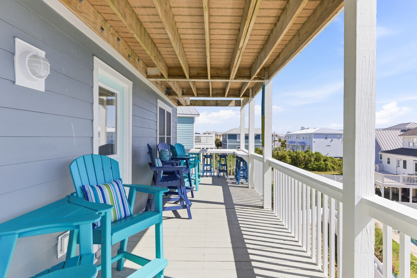 Settle into your private covered deck with colorful seating and distant views—perfect for morning coffee or unwinding after a beach day in the fresh coastal air.