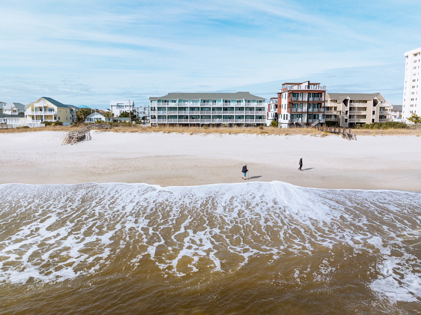 Pristine beachfront location with gentle waves and soft sand stretching along the coast, surrounded by charming vacation buildings.