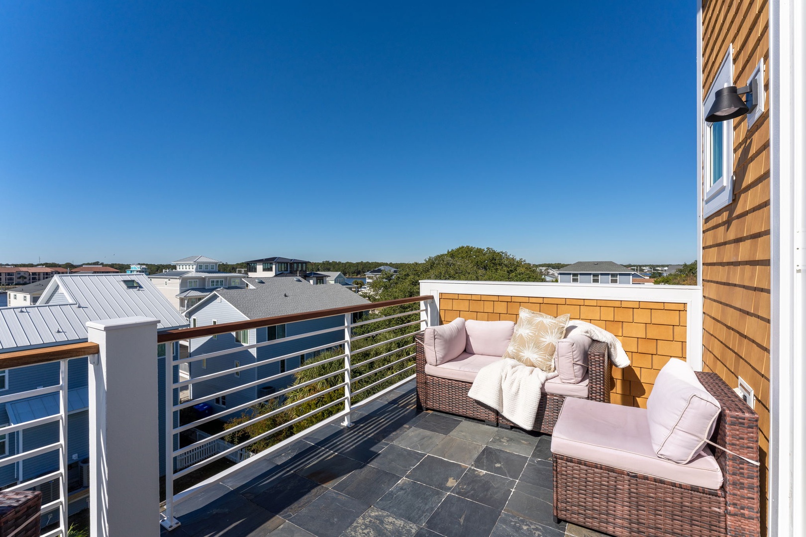 Unwind on your private balcony with cozy seating and sweeping neighborhood views under endless blue skies.