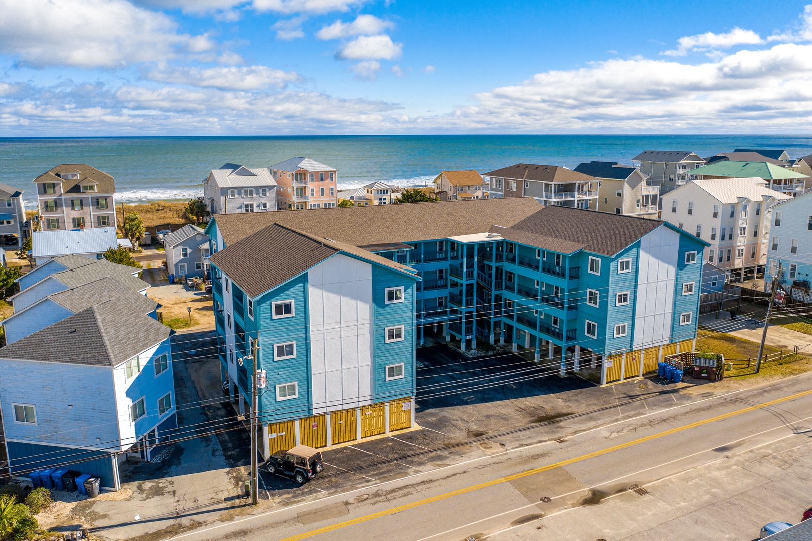 Beachfront vacation rental complex featuring bright blue buildings just steps from the ocean in a charming coastal community.
