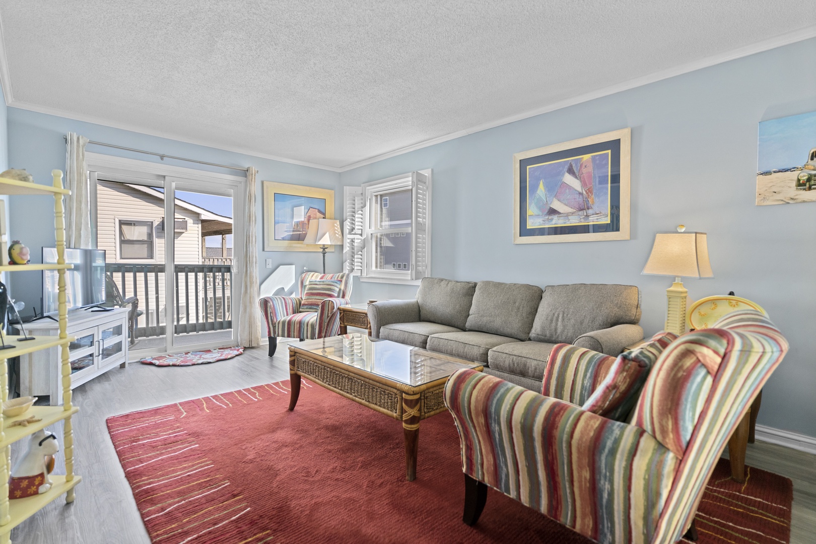 Relax in your coastal living room with comfortable seating, nautical artwork, and natural light streaming through large windows.