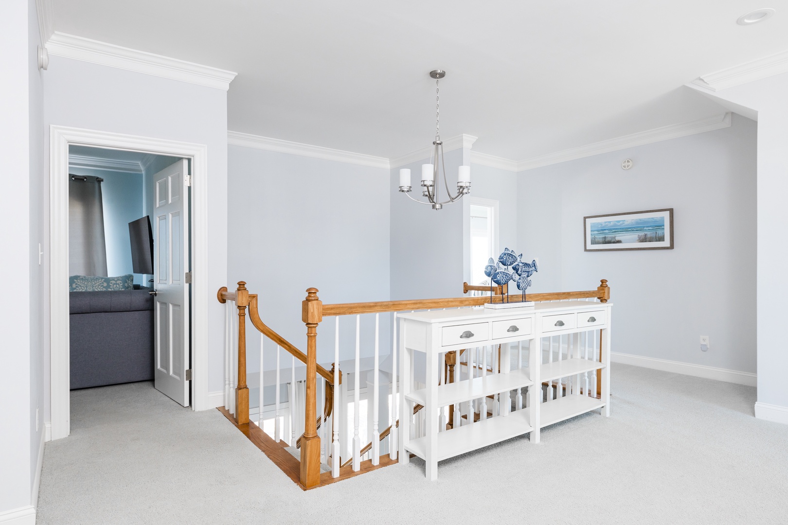 Relax in this bright upstairs landing with cozy seating and elegant chandelier lighting for your evening conversations.