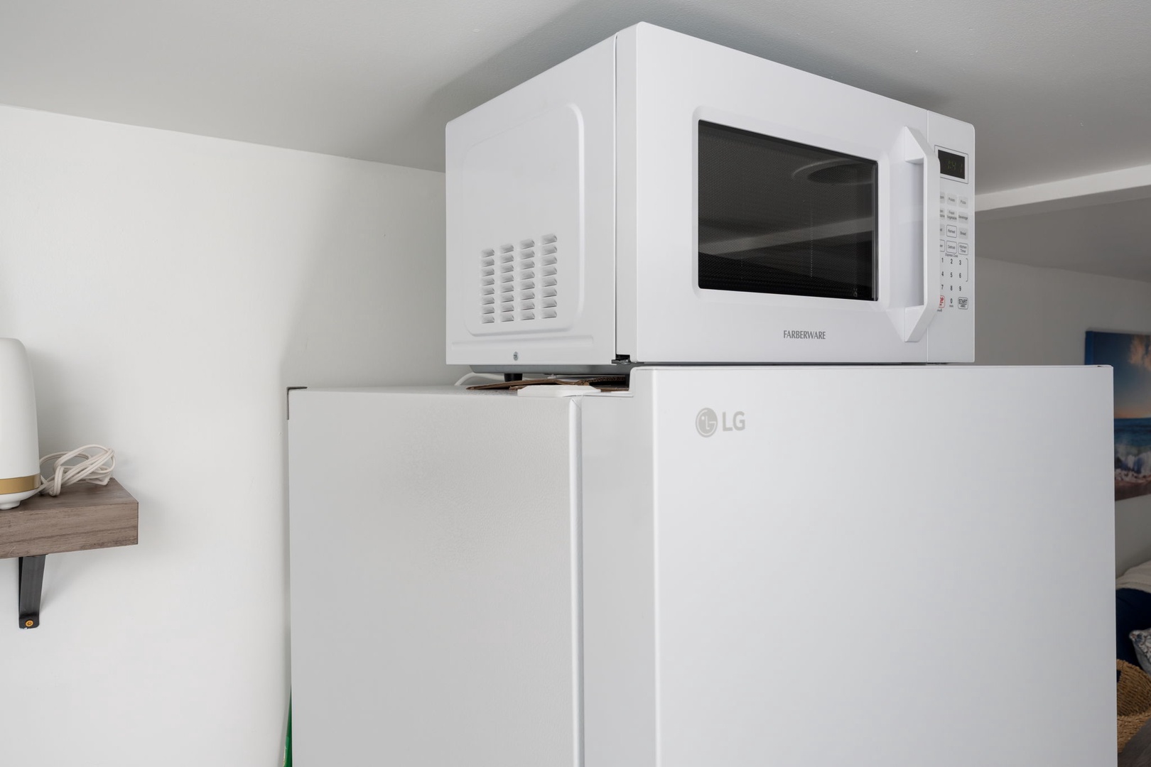 Your compact kitchen setup features a full-size refrigerator topped with a convenient microwave for quick meals and snacks.