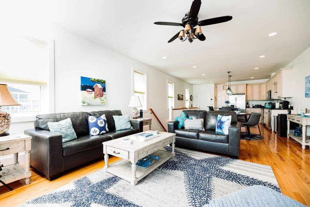 Relax in your spacious living room with comfortable leather seating and an open kitchen, perfect for coastal getaway conversations.