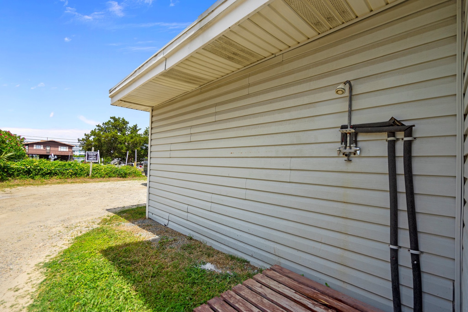 Property exterior featuring white siding and outdoor shower setup in a residential neighborhood setting.