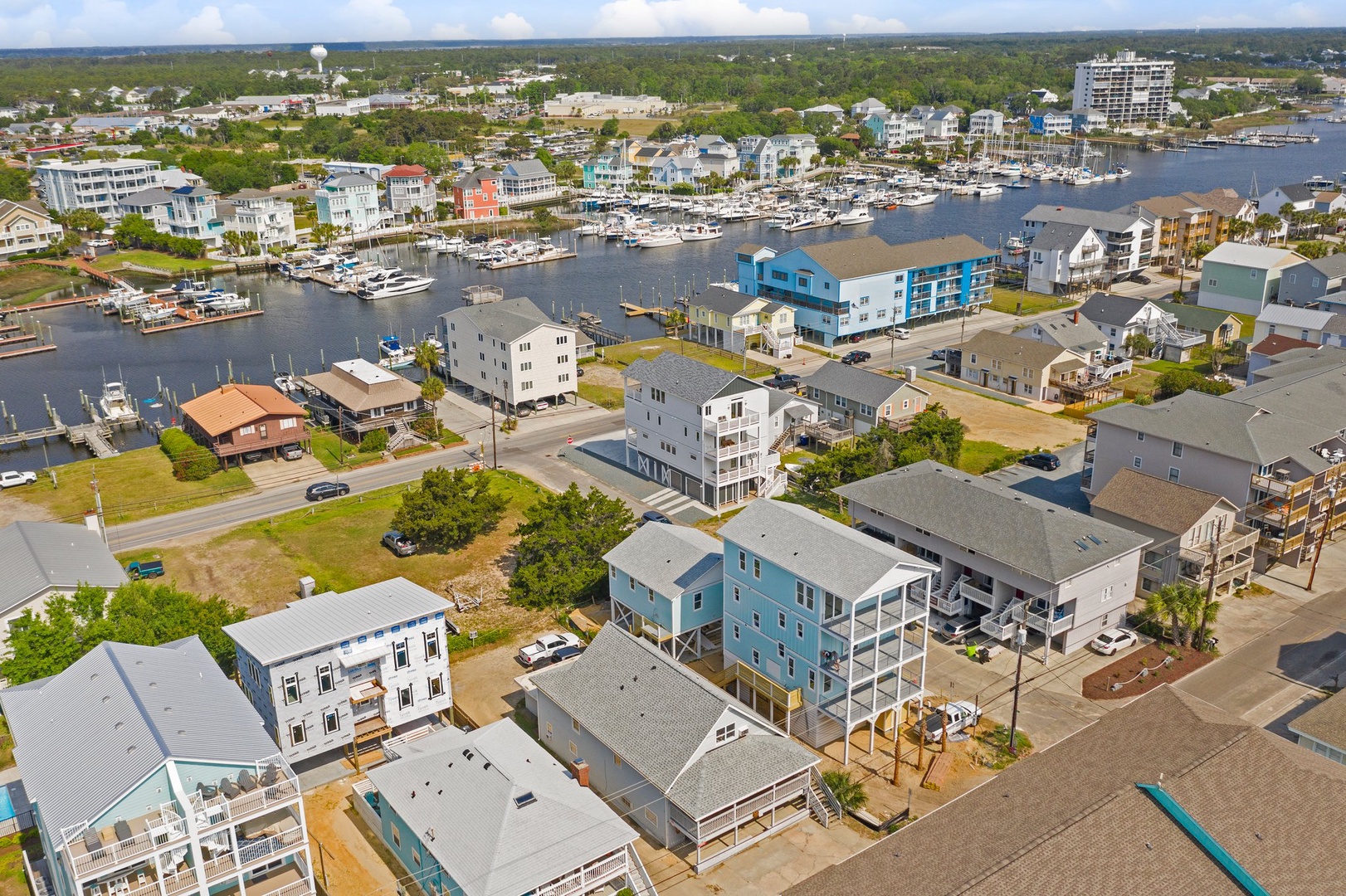 Aerial view of a vibrant coastal community featuring colorful waterfront homes, marina access, and diverse vacation rental properties near the harbor.