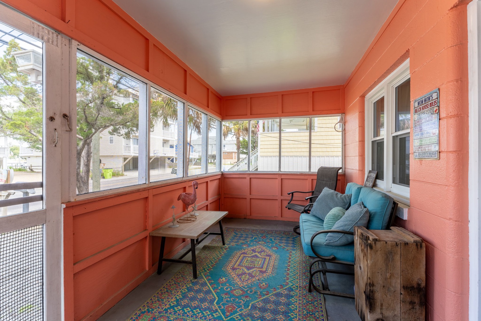 Your private enclosed porch invites you to unwind with plush seating and colorful décor, offering peaceful neighborhood views through large windows—perfect for morning coffee or evening relaxation.