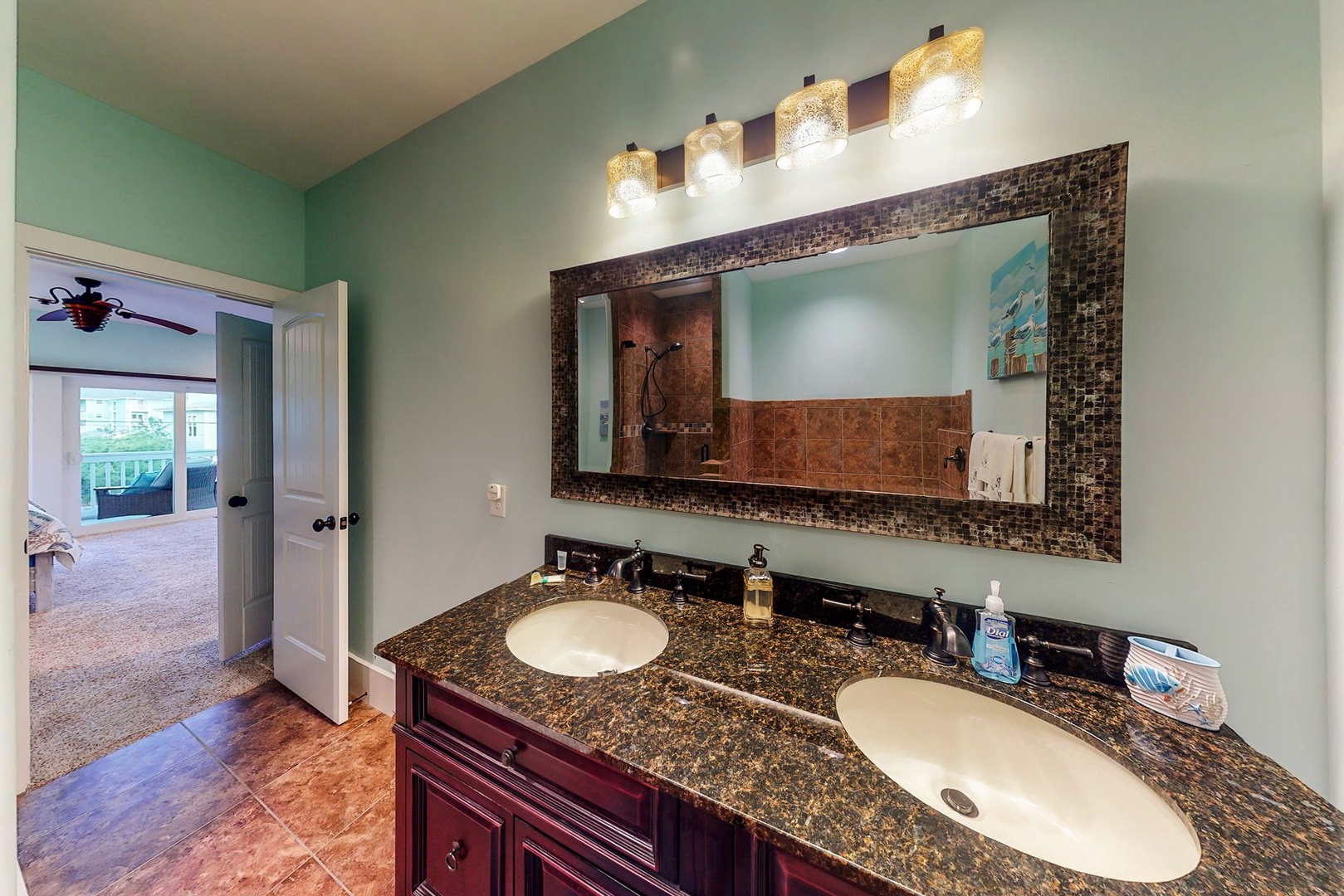 Your spacious bathroom features elegant granite countertops, dual sinks, and a stunning mosaic mirror frame with warm vanity lighting.