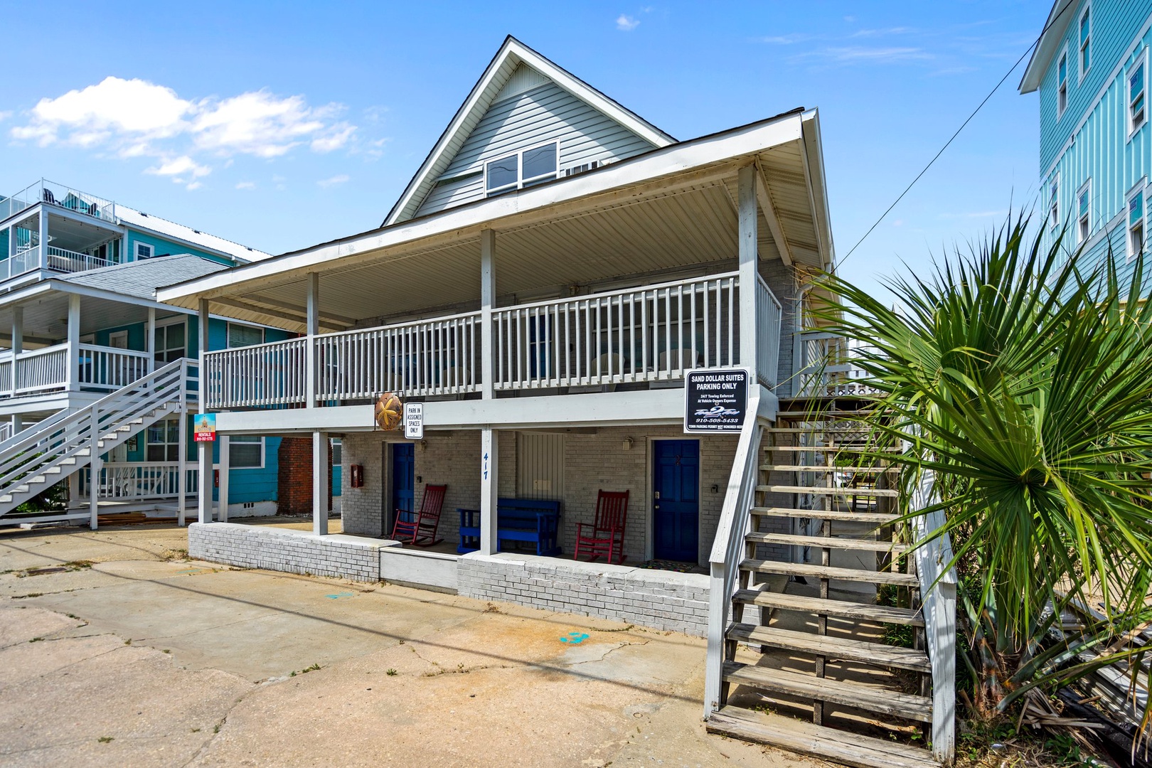 Charming coastal property featuring traditional beach house architecture with covered porches and tropical palm landscaping in a sunny beachside neighborhood.