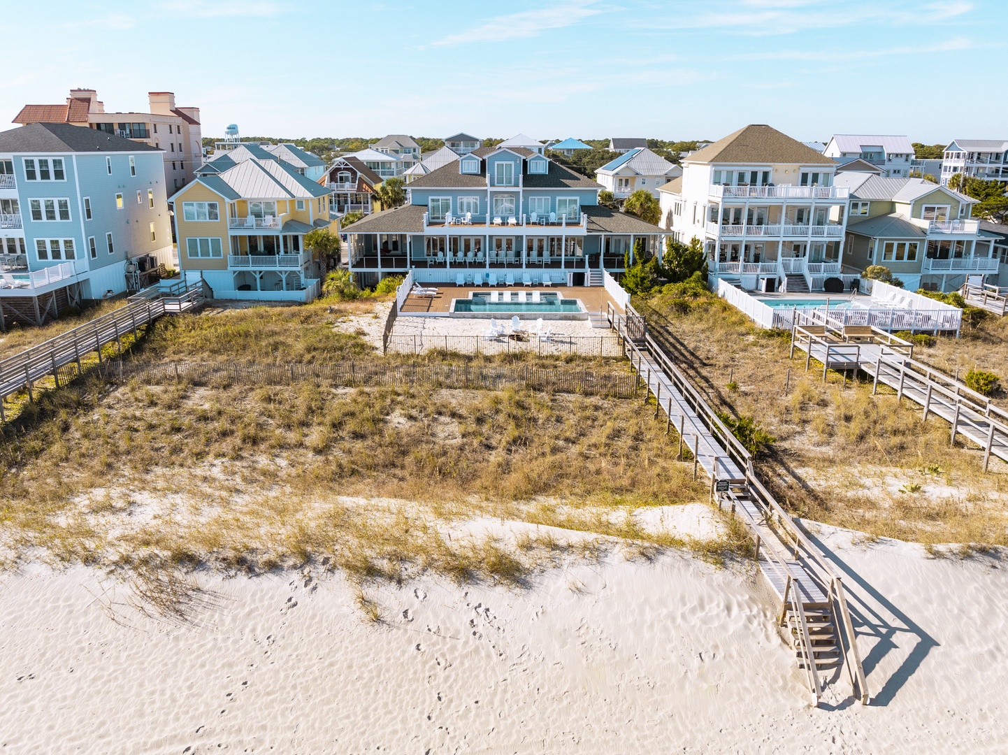 Aerial view of beachfront vacation homes with private pool and direct beach access via wooden walkway.