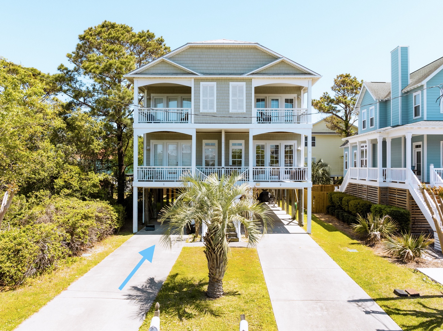Coastal beach house featuring covered balconies and tropical landscaping in a charming neighborhood setting.