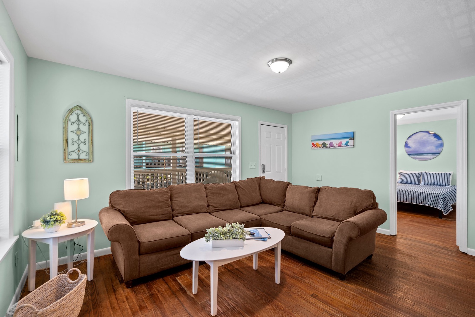 Sink into the plush sectional sofa in your calming mint-green living room, where natural light and warm hardwood floors create the perfect space to unwind.