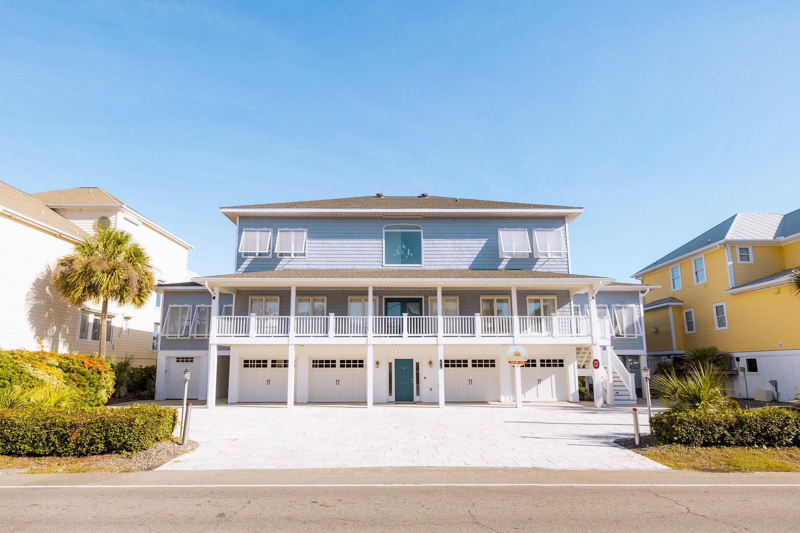 Coastal vacation home with wraparound porch and palm trees set in charming beachside neighborhood.