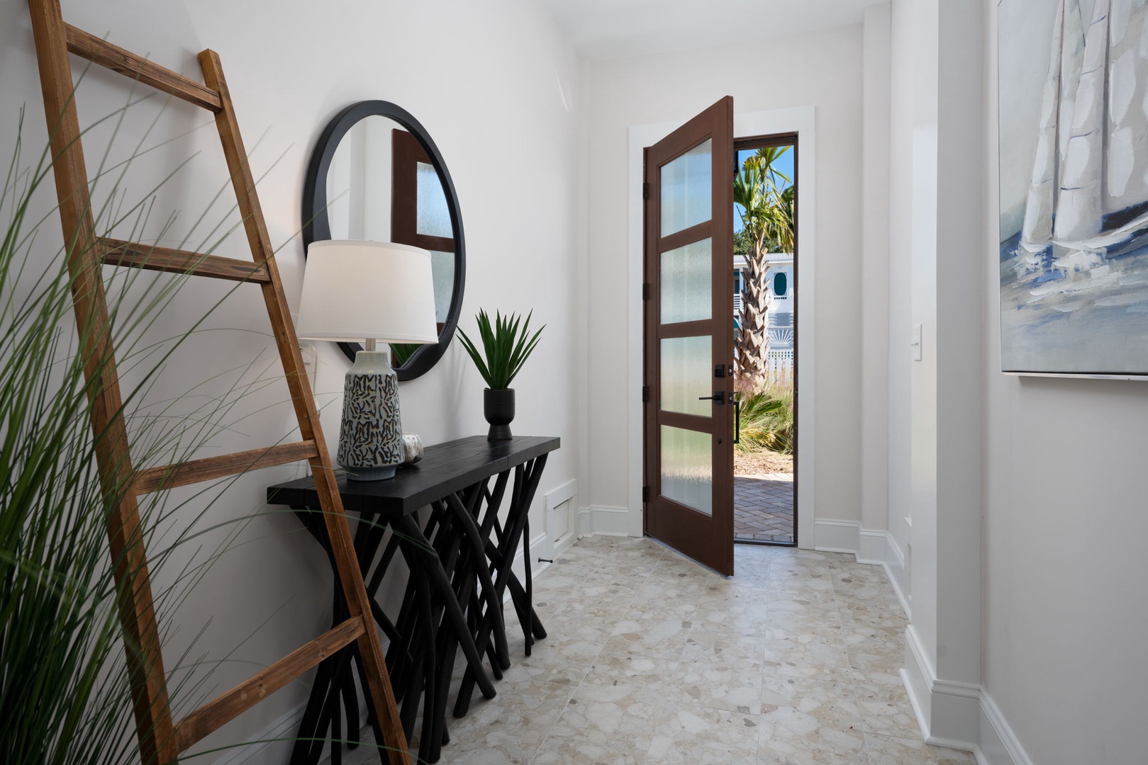 Your stylish entry welcomes you with warm wood tones, elegant décor, and glimpses of tropical paradise beyond the glass doors.