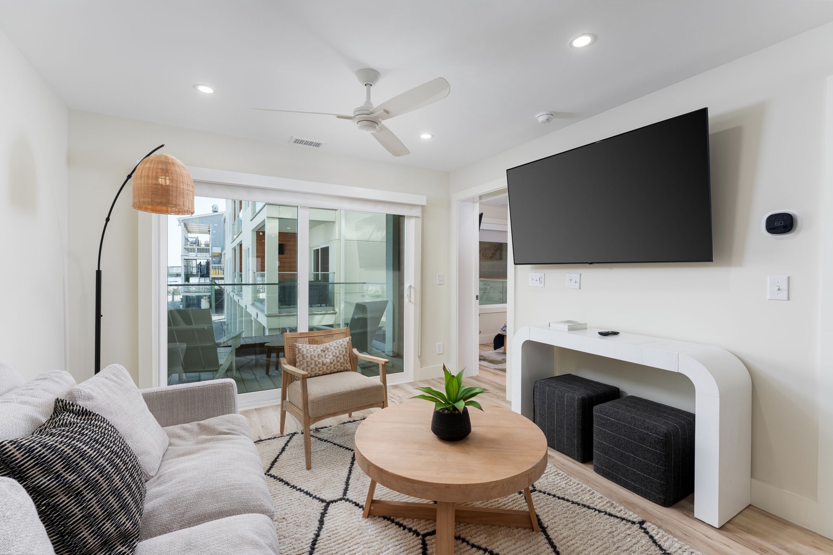 Unwind in your stylish living room with sleek TV, cozy seating, and glass doors opening to a private outdoor space.