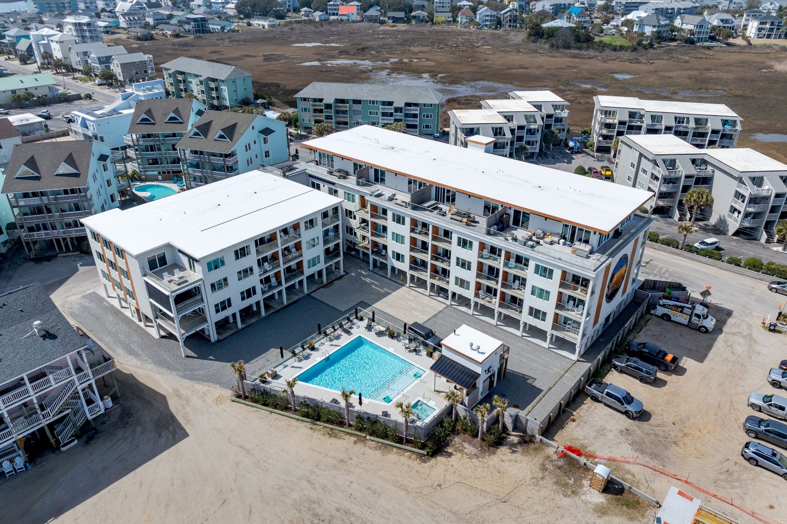 Modern beachside resort complex featuring contemporary architecture with swimming pool and convenient parking in a vibrant coastal community.