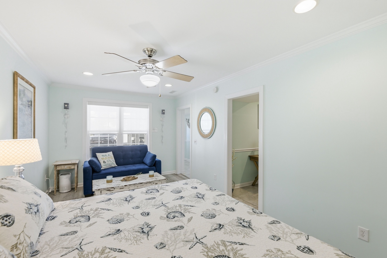 Picture yourself relaxing in this coastal-inspired retreat, where soft sea-foam walls and ocean-themed bedding set a calming tone. The cozy sofa invites you to unwind while taking in the view through your private window.