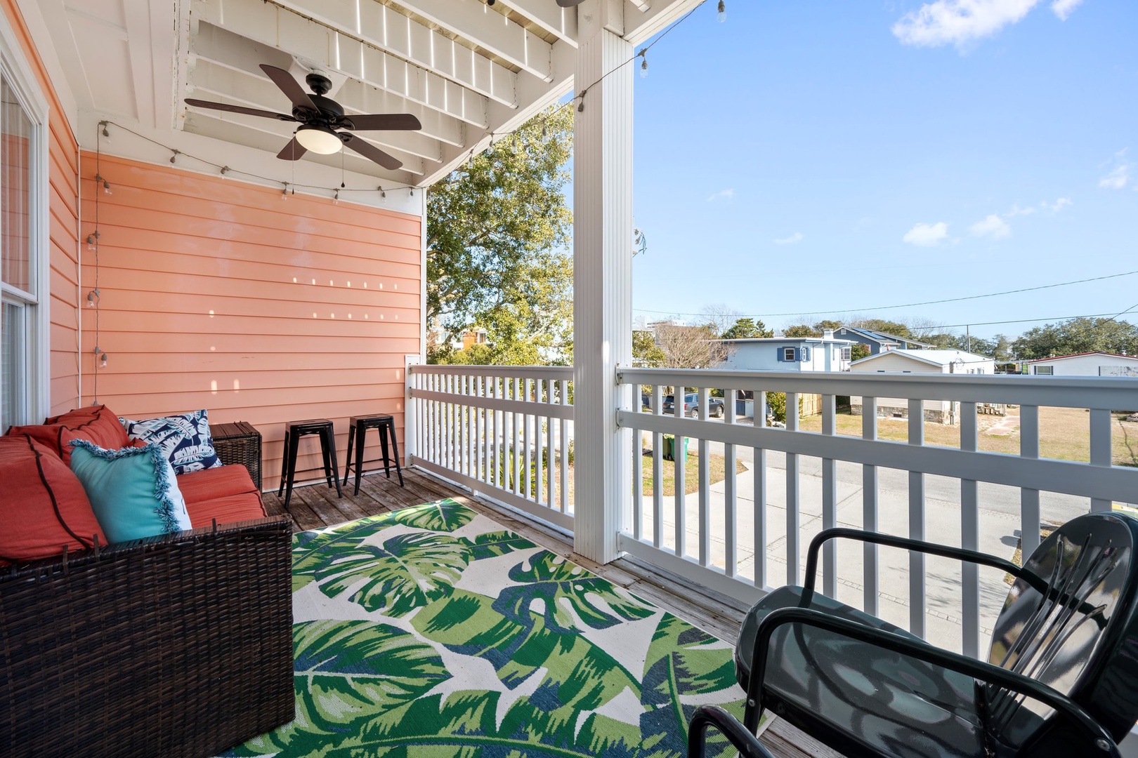 Relax on your private covered balcony with comfy seating, tropical-themed decor, and gentle ceiling fan breezes.