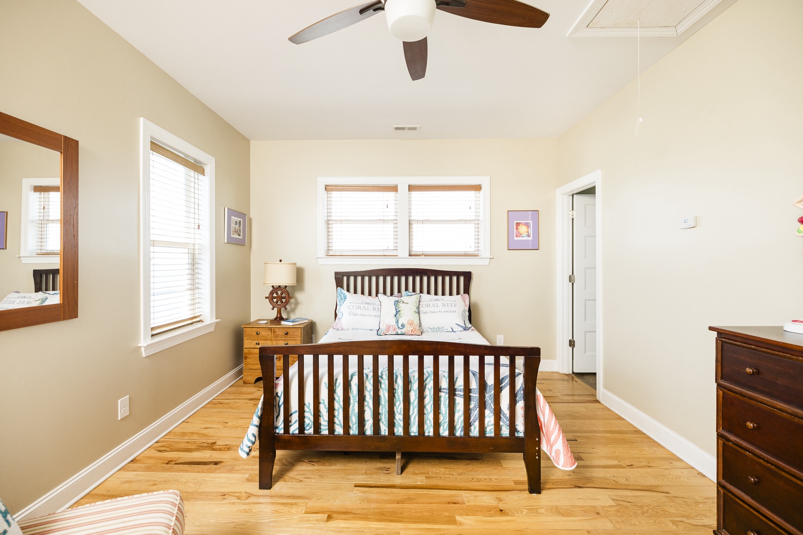 Rest peacefully in this bright bedroom with warm wood floors, ceiling fan, and charming nautical touches throughout.