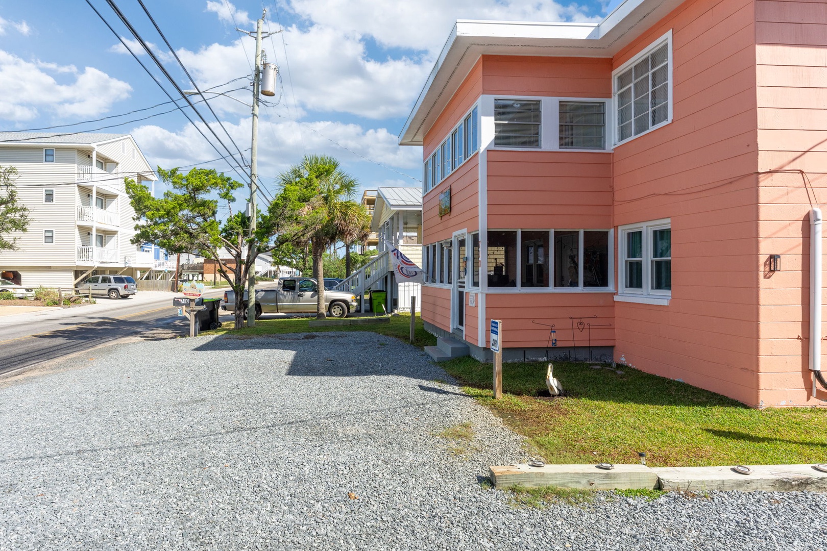 Charming coral-colored beach house with convenient gravel parking and peaceful neighborhood setting.