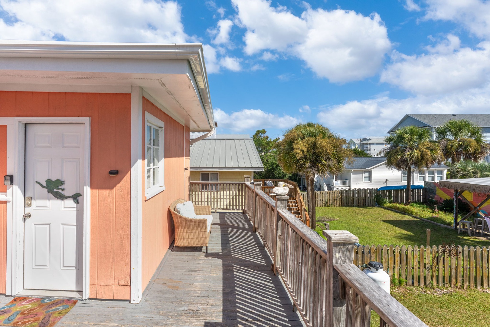 Step onto your private deck with peaceful wicker seating, overlooking the lush yard and coastal neighborhood.