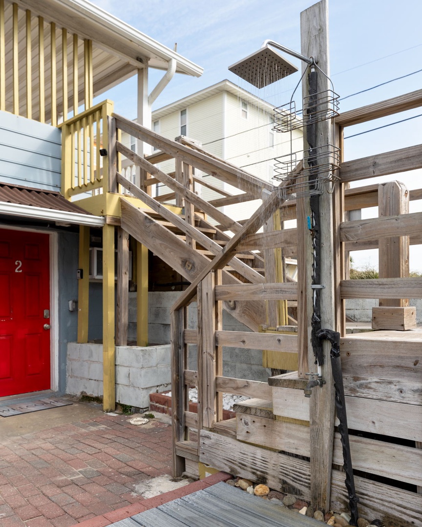 Charming wooden stairs lead to elevated accommodation with colorful doors marking your welcoming beachside retreat.
