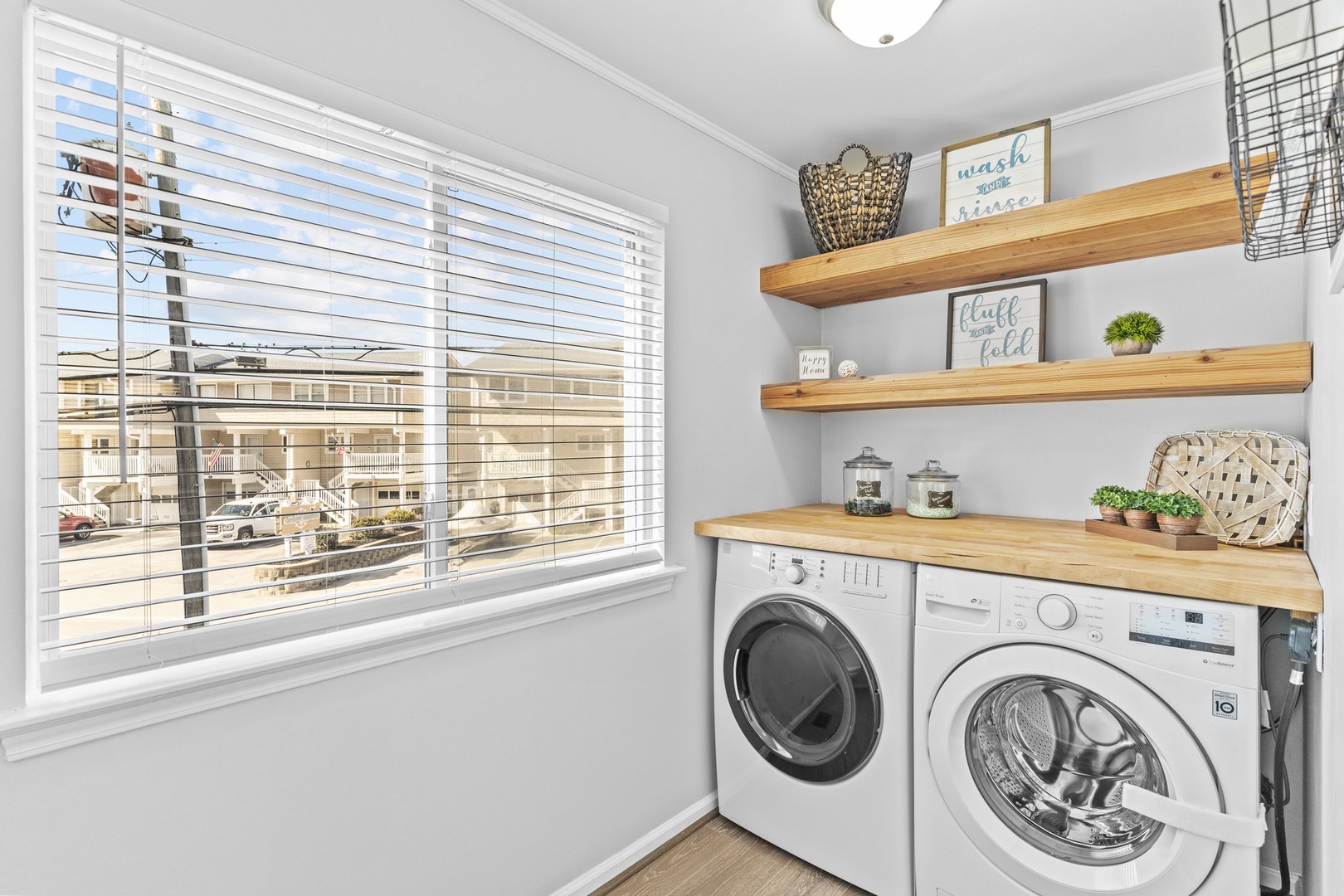 Your dedicated laundry space features modern appliances beneath warm wood shelving, perfectly organized for your convenience during longer stays.