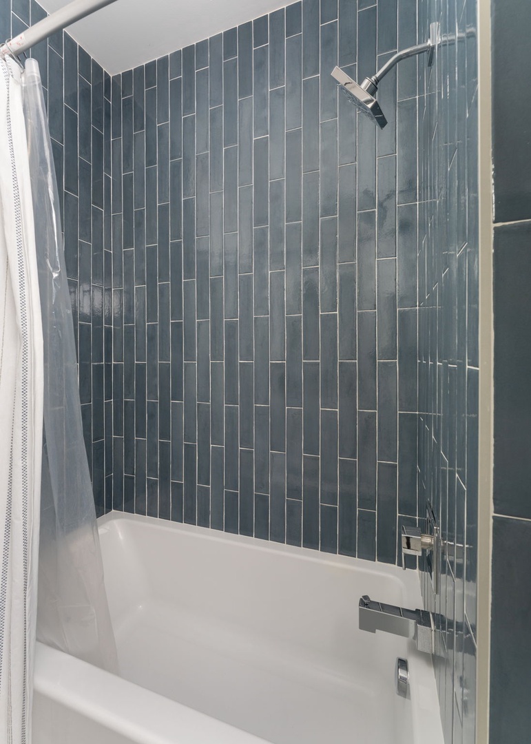 Unwind in your elegant bathtub surrounded by stunning blue subway tiles and modern fixtures for the perfect relaxing soak.