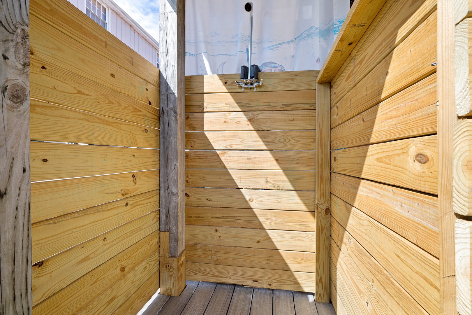 Step into your private outdoor shower, where natural wood walls create an intimate spa-like retreat under the open sky.