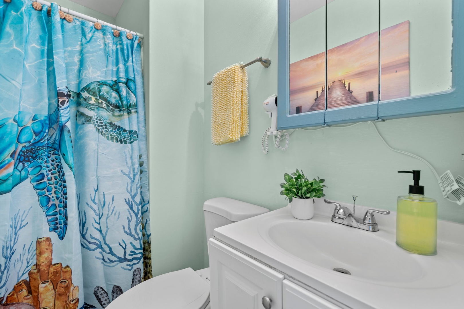 Refresh in your coastal-themed bathroom featuring ocean-inspired decor, a vanity with thoughtful amenities, and soothing sea turtle artwork.