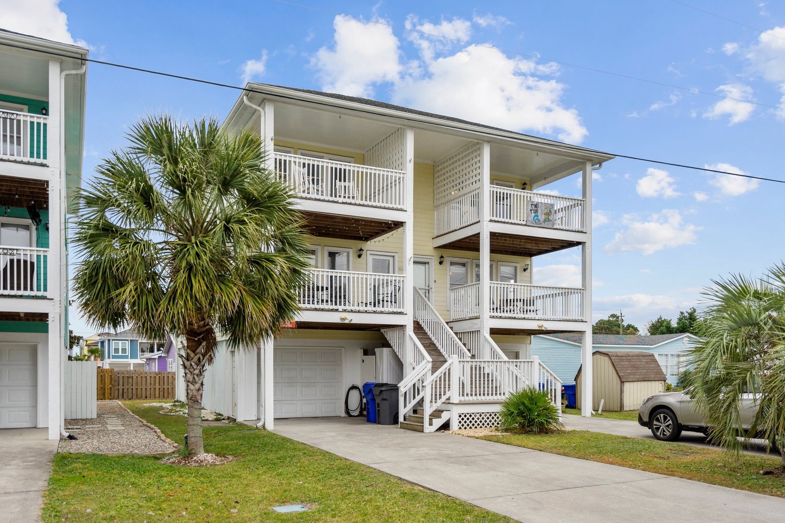 A welcoming beach house with spacious multi-level balconies and tropical landscaping in a peaceful residential neighborhood.