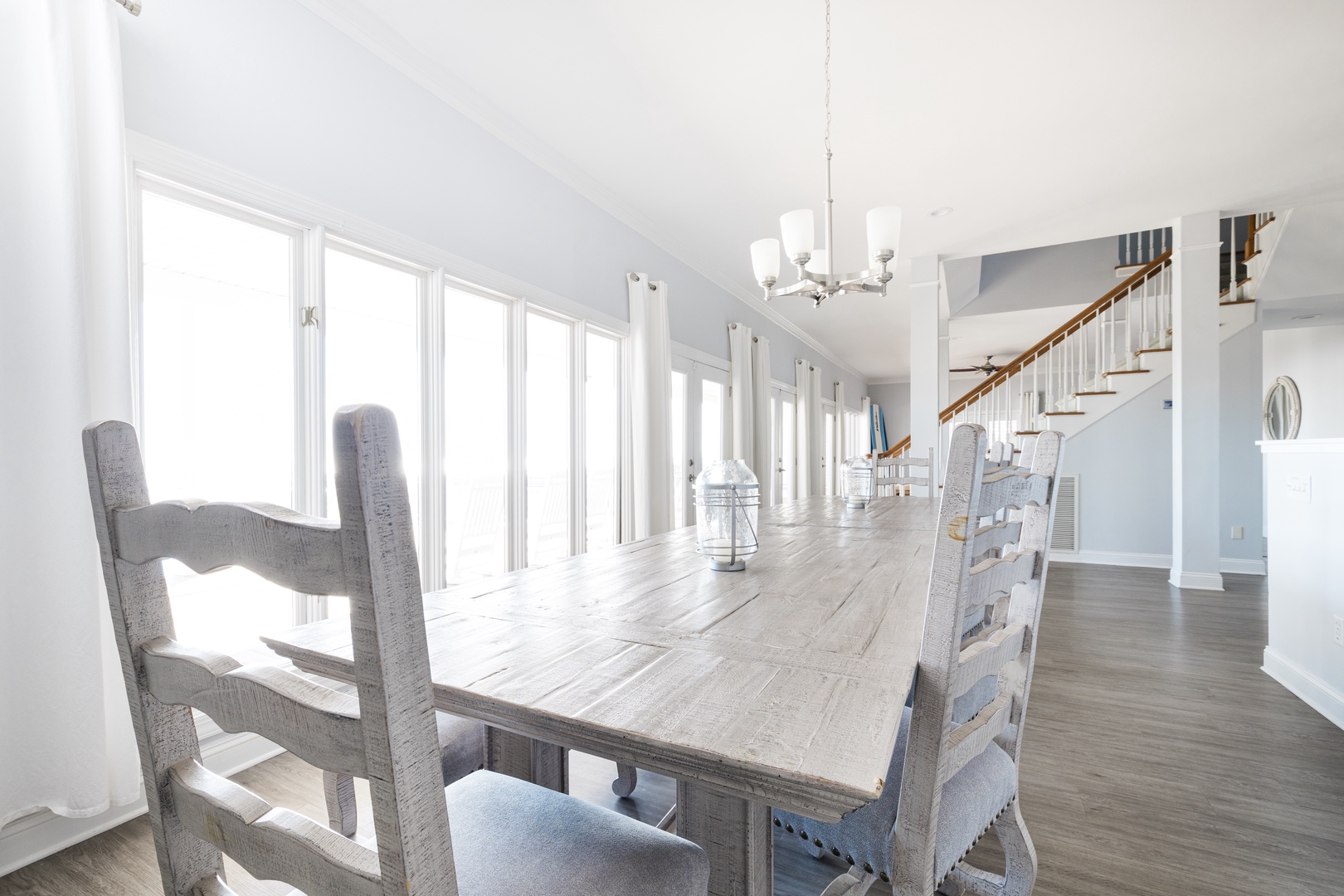 Gather around this stunning farmhouse dining table where sunlight streams through floor-to-ceiling windows, creating the perfect setting for memorable meals together.