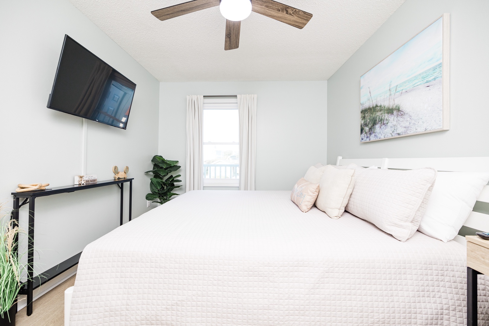 Drift off to peaceful sleep in your bright, airy bedroom with calming coastal artwork and modern comforts like a wall-mounted TV and ceiling fan.