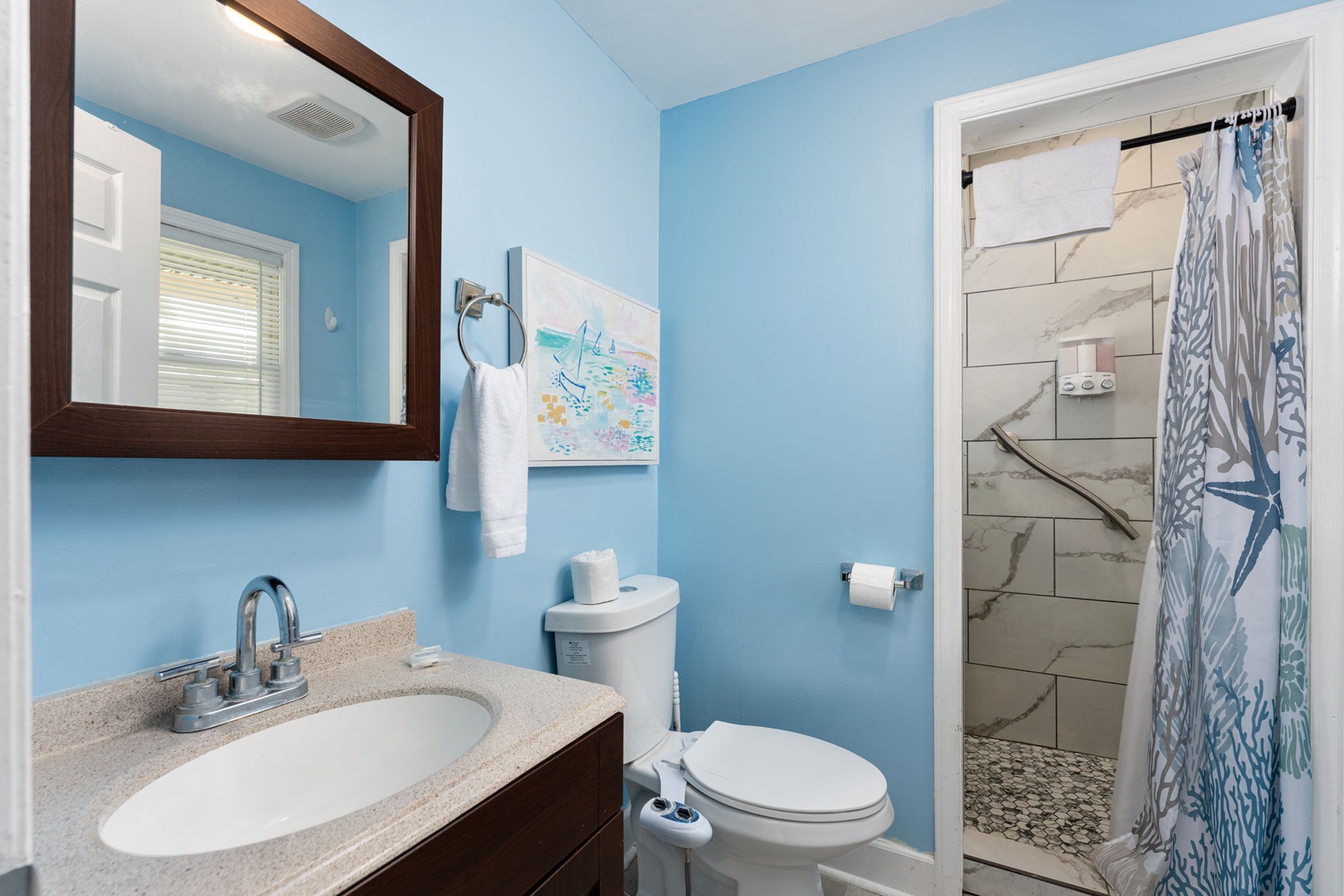 Freshen up in your private bathroom, complete with a vanity, shower, and coastal charm—everything you need for a comfortable stay.
