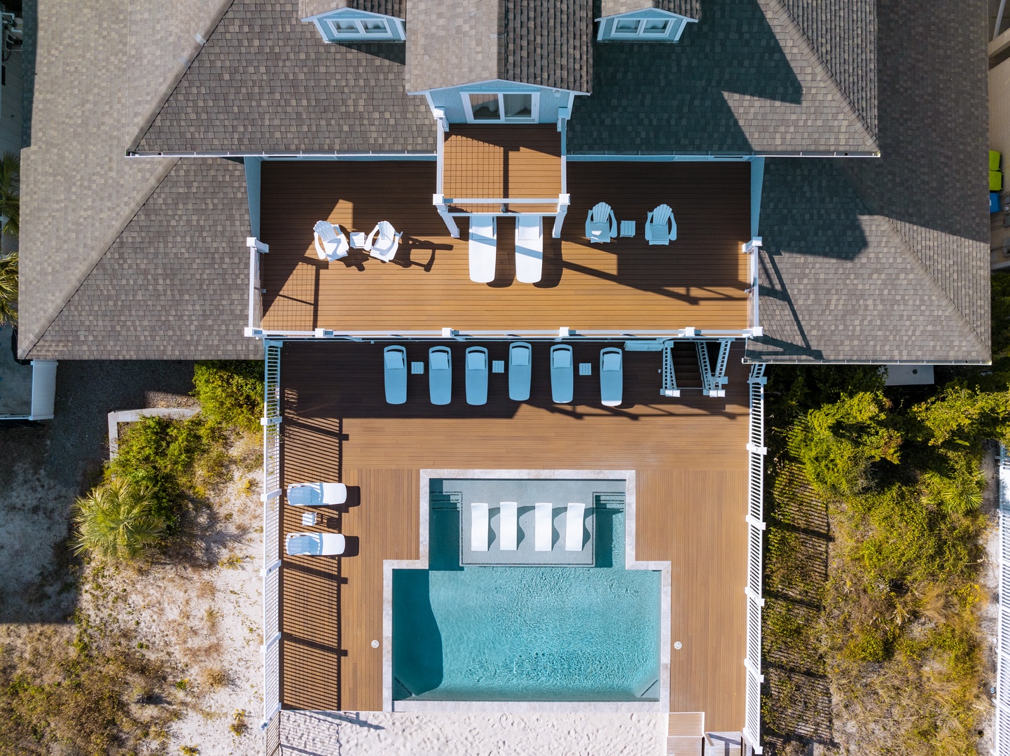 Stunning aerial view of the property showcasing a pristine swimming pool surrounded by elegant wooden decking and modern architectural design.
