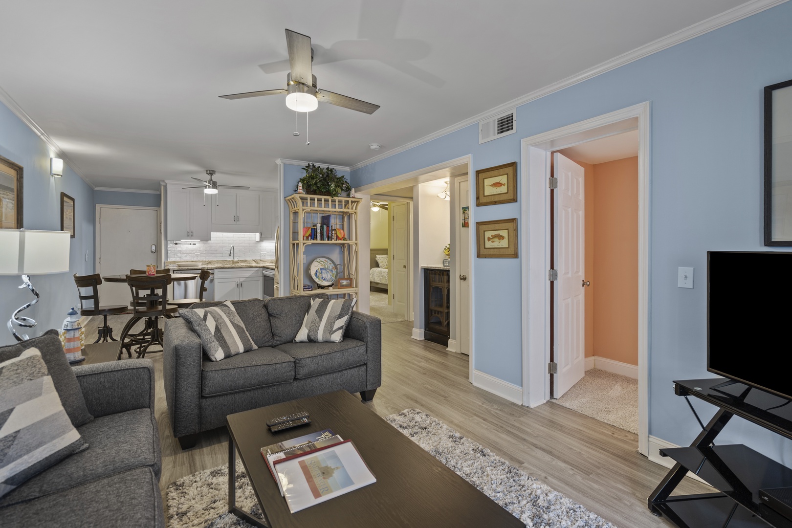 Relax in your bright, airy living space featuring comfortable seating, modern ceiling fans, and an open layout connecting to your fully-equipped kitchen.