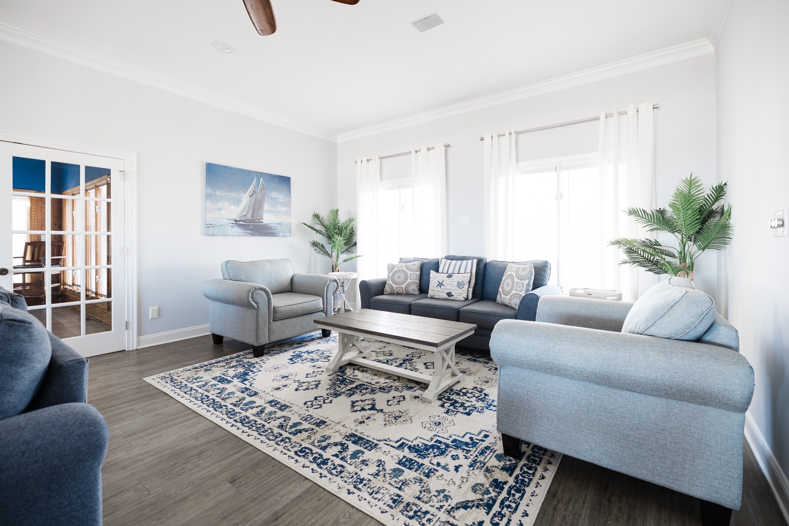 Relax in your bright coastal-inspired living room with plush seating, nautical artwork, and tropical plants creating a serene beachside retreat.