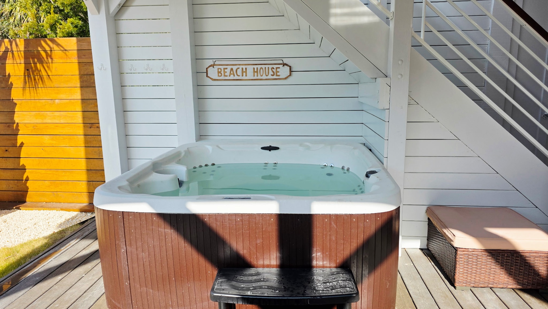 Sink into your private hot tub beneath the Beach House sign, where warm bubbles melt away stress in your coastal retreat.