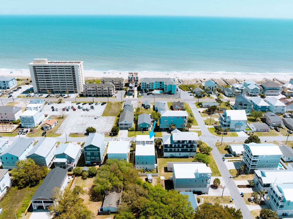 Aerial view of coastal community with beachfront properties and turquoise waters stretching to the horizon.