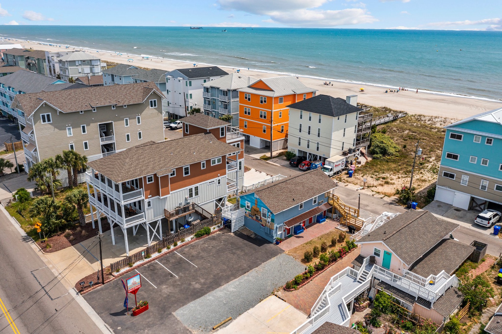 Aerial view of colorful beachfront vacation rental properties along pristine sandy shores with turquoise waters beyond.