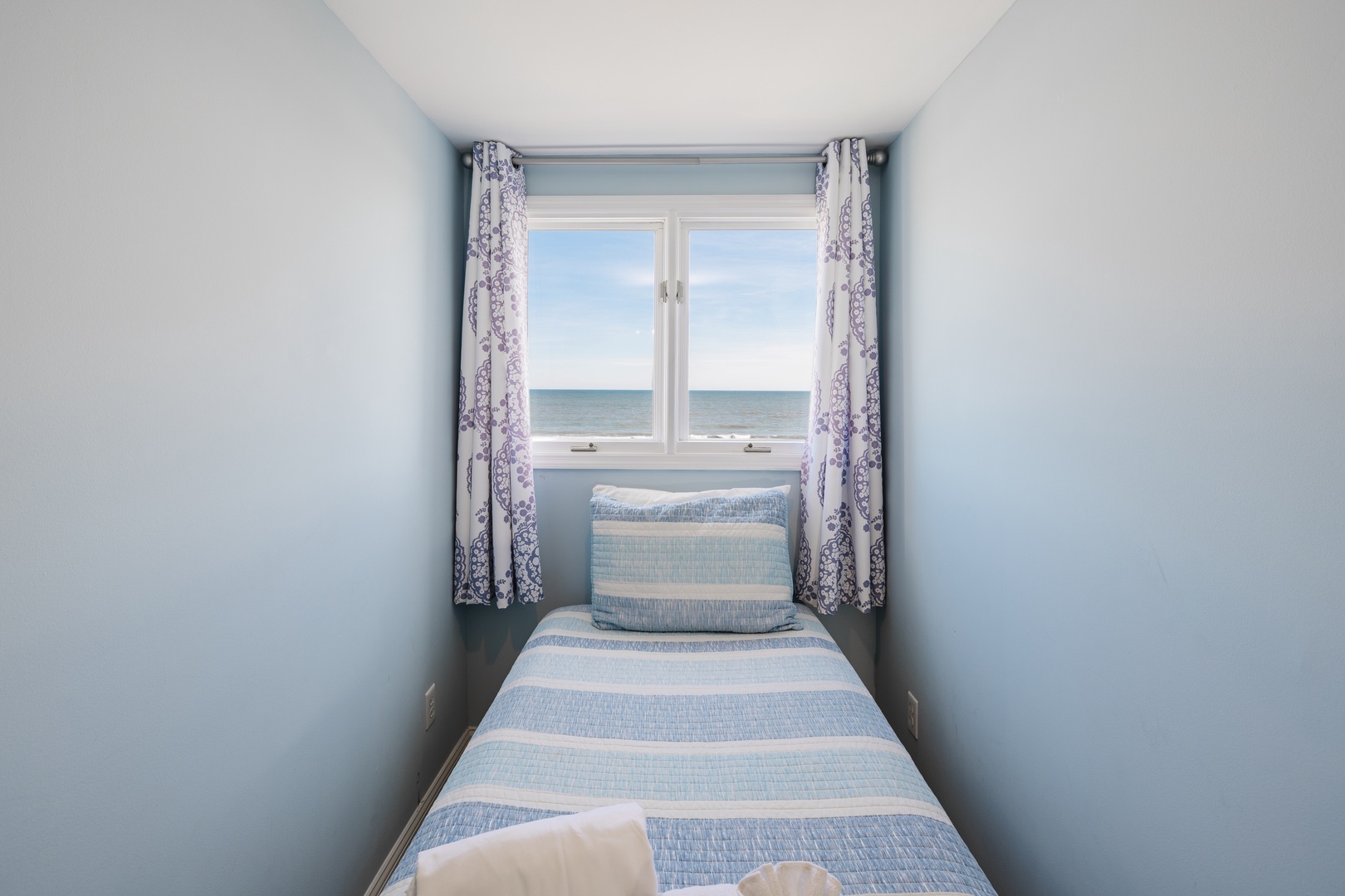Wake up to endless ocean views from your cozy bed, where soft blue linens mirror the sea beyond your window.