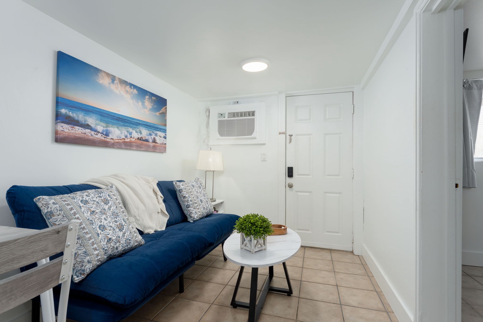 Sink into the plush navy sofa surrounded by crisp whites and coastal charm, where your peaceful retreat begins.