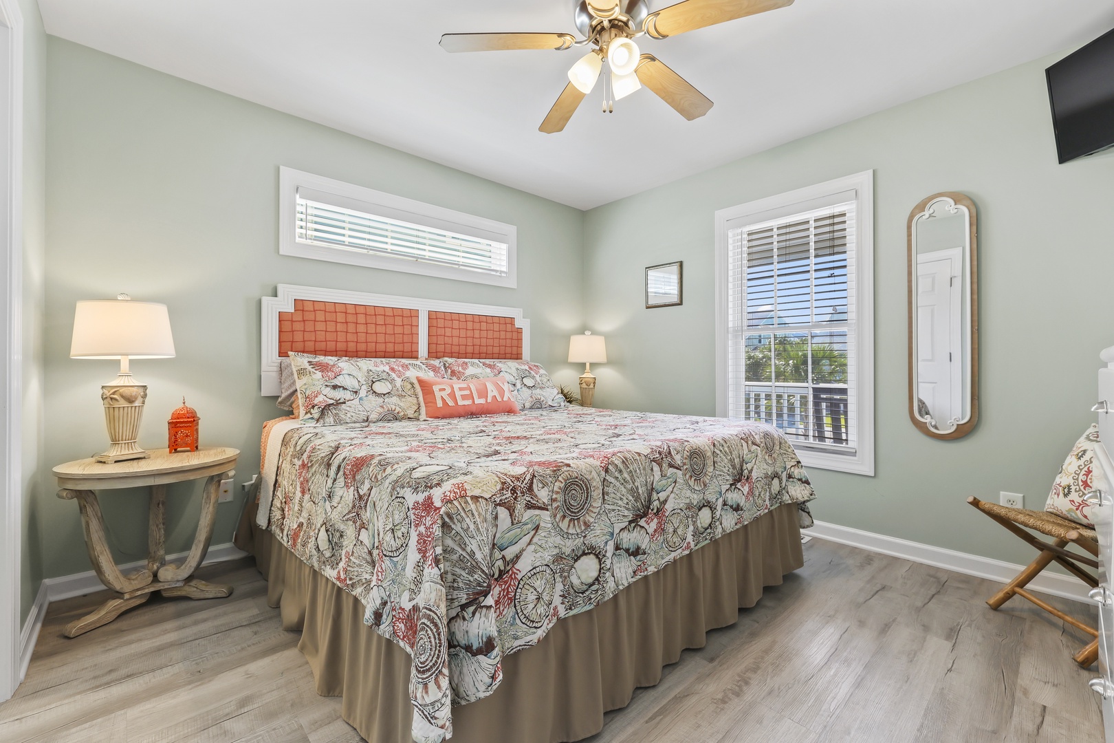 Sink into your plush bed under the gentle whirl of the ceiling fan, with natural light streaming through the windows and coastal-inspired decor inviting you to unwind.