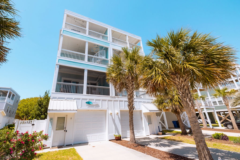 Modern coastal property with tropical landscaping and bright blue skies, creating an inviting beachside atmosphere.