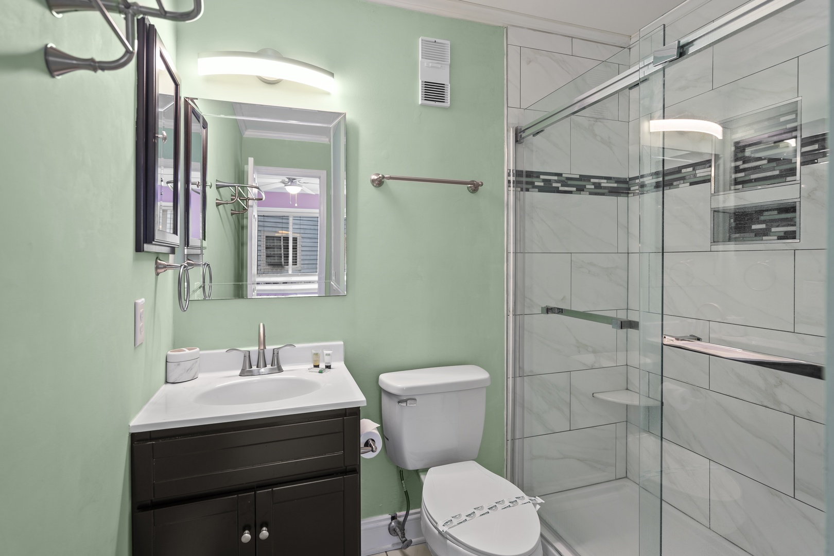 Refresh in your private spa-like bathroom with contemporary tile work, glass shower, and soothing green walls.