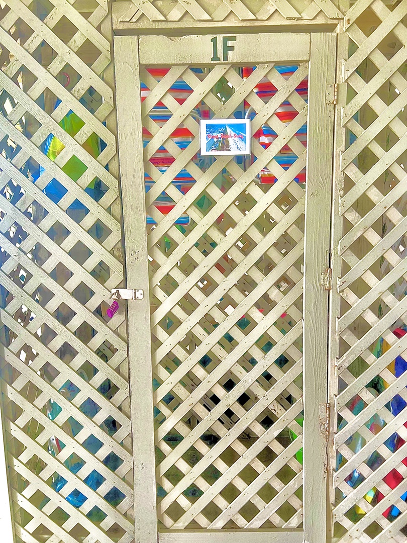 A charming white lattice gate displays '1F' marking, adorned with colorful geometric patterns and a small welcome sign.