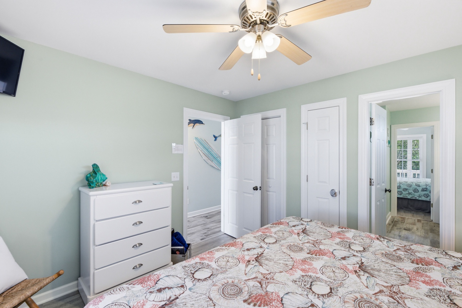 Relax in your peaceful bedroom with calming coastal hues, a comfortable bed, ceiling fan, and charming ocean-themed touches that set the tone for your beach getaway.